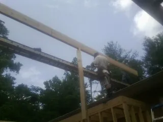 Carpenter setting a ridge beam over a new addition frame — Ice Dam Removal by Roofing Brothers in Massapequa