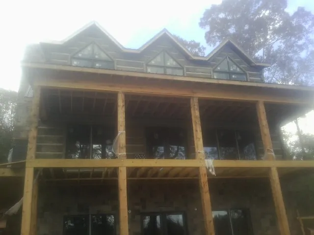 Dormers and porch framing on a large log home under construction — Roof Coating work by our crew in Massapequa