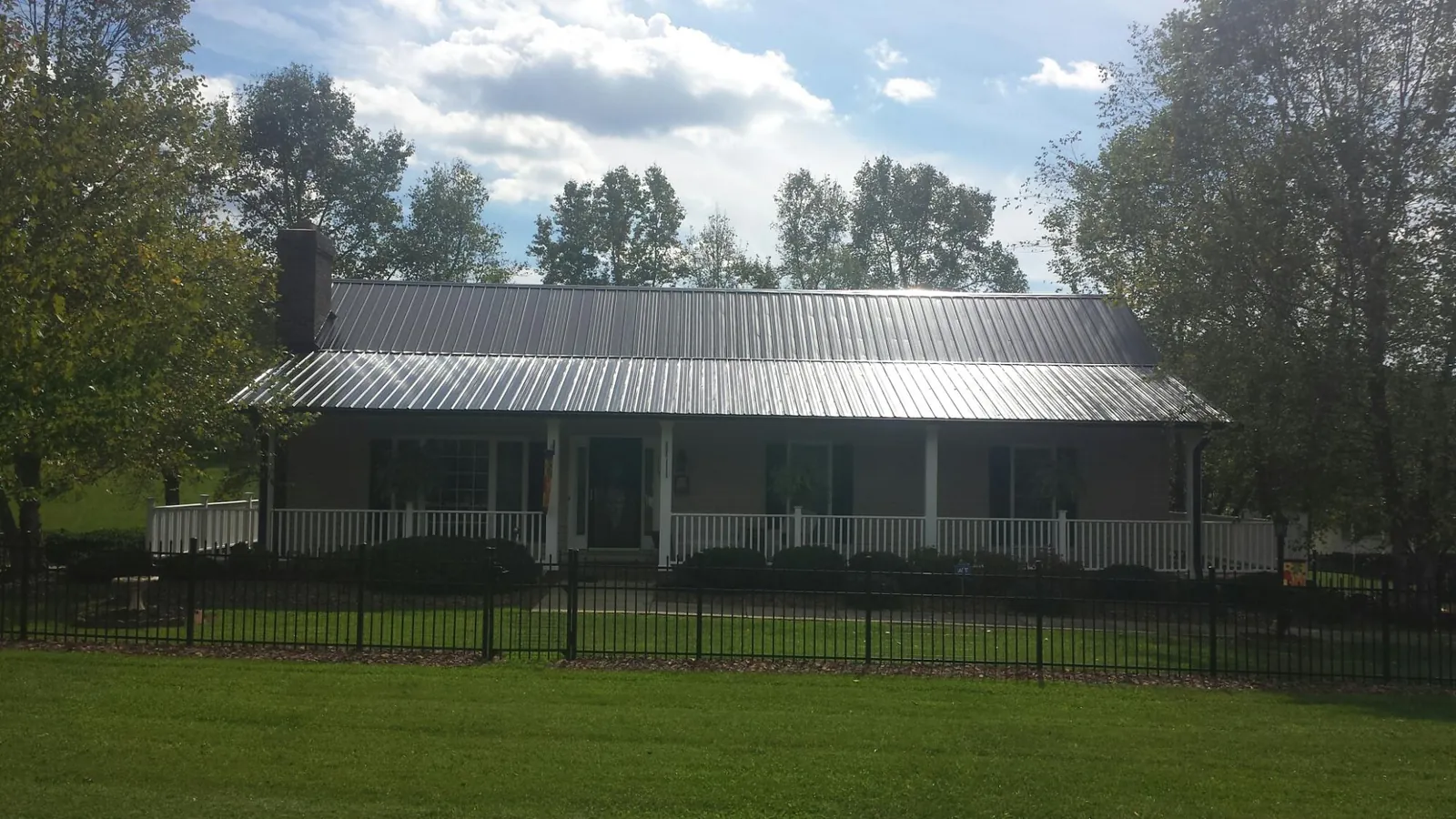 Gray metal roof on a brick ranch with a full width front porch — Gutter Guard Installation work by our crew in Massapequa