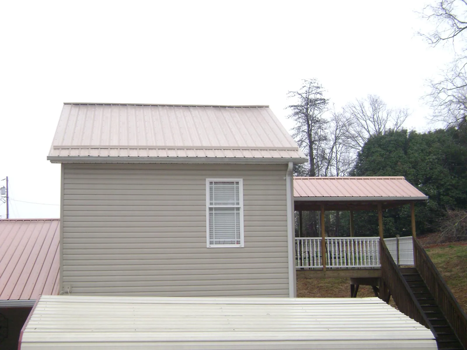 Tan metal roofs on a two story addition and attached porch, from a Roof Replacement job in Massapequa