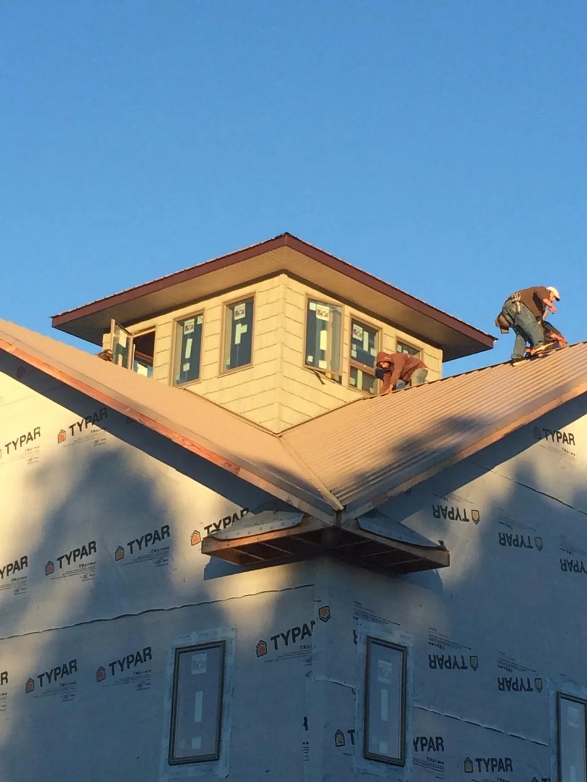 Roofers working around a rooftop cupola on a new metal roof at sunset — Roof Waterproofing in Massapequa by Roofing Brothers